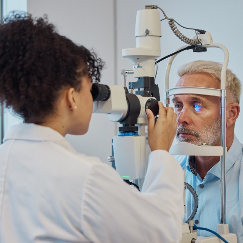 Vision, eye exam and healthcare with a doctor woman or optometrist testing the eyes of a man patien Vision, eye exam and healthcare with a doctor woman or optometrist testing the eyes of a man patien